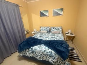 Schlafzimmer mit einem Bett mit blauer Bettwäsche und Kissen in der Unterkunft Casa Palm and Tide holiday home in Swakopmund