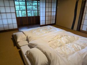 a large white bed in a room with windows at 信州の古民家宿 真秀ろばmahoroba in Nagano