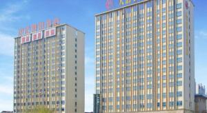 twee hoge gebouwen met een bord erop bij The Long Red Hotel Daye Huangshi in Daye