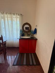 une salle de bain avec une armoire rouge et un miroir dans l'établissement Hideaway villa, à Varkala