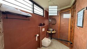 a bathroom with a toilet and a window at 2BR Forest Cabin, Jacuzzi, Fireplace & Mt Kenya Views in Naro Moru