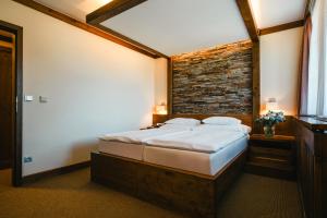 Un dormitorio con una cama con una pared de ladrillos. en Wellness hotel Horal, Velké Karlovice, en Velké Karlovice 50 fotos más