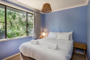 a blue bedroom with a large bed and a window at Tranquil Waters in Quindalup