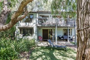 a house with a deck and a chair in the yard at Tranquil Waters in Quindalup