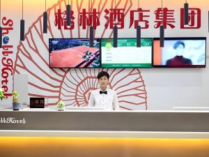 een man staat achter een toonbank in een televisie bij Shell Zhengzhou North Third Ring University Science and Technology Park Hotel in Laoyachen