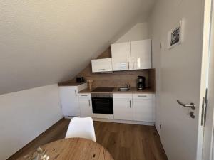 eine kleine Küche mit weißen Schränken und einem Tisch in der Unterkunft Kato Suite in Oldenburg