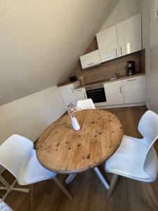 ein Holztisch und weiße Stühle in einer Küche in der Unterkunft Kato Suite in Oldenburg + 4 Fotos