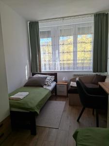 a room with two beds and a couch and a window at Centrum apartman in Szekszárd