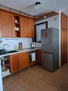 a kitchen with wooden cabinets and a stainless steel refrigerator at Centrum apartman in Szekszárd