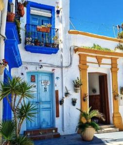 a blue and white building with a blue door and plants at La Casa del Cine en Níjar in Níjar