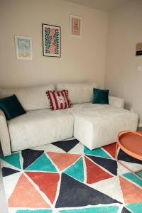 a living room with a white couch and a colorful rug at Maison MUGUET 2 SPA-PARKING-COLMAR in Wickerschwihr