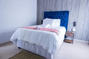 a bedroom with a large bed with a blue headboard at Towny Lodge in Kokstad