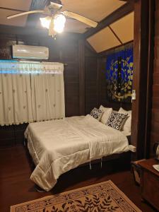 Un dormitorio con una cama y un ventilador de techo. en Huen Tip Viman, en Ban Nong Ho