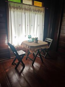 una mesa con dos sillas y una ventana con mariposas en Huen Tip Viman, en Ban Nong Ho