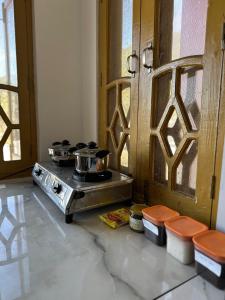 Una cocina con una estufa con ollas y sartenes encima. en La Casa by Cosmic Kriya, en Bīr