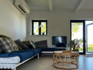 Una sala de estar con un sofá azul y un televisor en Holiday Home With View Of Dalby Bay, en Mesinge