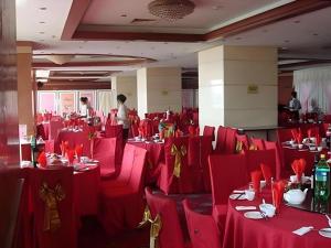 a room with red tables and chairs with people in the background at Qingdao Donghai Hotel in Qingdao