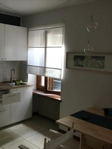 a kitchen with white cabinets and a window with a blind at Cormòns 2# in Cormòns +2 photos