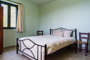 1 Schlafzimmer mit einem Bett mit rosa Kissen und 2 Stühlen in der Unterkunft Mountain Retreat in Kyperounta + 4 Fotos