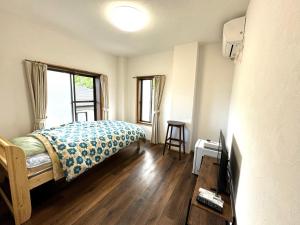 a bedroom with a bed and a tv and a window at 徳之島体験お宿結屋 in Inokawa