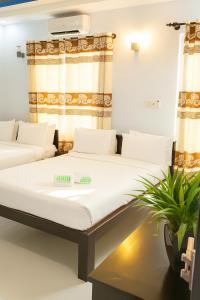 two beds in a room with a plant at Đại An Hotel Bến Tre in Ben Tre