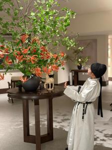 a woman standing next to a table with a plant at Xi'an MC City Courtyard Hotel - A st andalone hotel by the city wall - Close to the bell tower and yongning gate - Designed in song dynasty aesthetic style - It features private courtyard and garden rooms - Integrating the historical culture of Xi'an in Xi'an