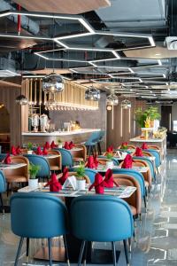 a restaurant with blue chairs and tables with red flowers at Bcons City Hotel in Dĩ An