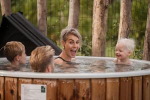 una mujer y dos niños en una bañera de hidromasaje en Hofparken De Bergvennen, en Lattrop