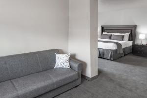
a hotel room with a couch, chair and a lamp at Baymont by Wyndham Glenview in Glenview

