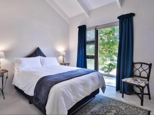 a bedroom with a bed with blue curtains and a window at Manhattan Estates - Plettenberg Bay in Plettenberg Bay