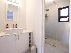 a white bathroom with a sink and a shower at Manhattan Estates - Plettenberg Bay in Plettenberg Bay
