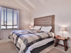 a bedroom with a bed with a plaid blanket and a window at Manhattan Estates - Plettenberg Bay in Plettenberg Bay +194 photos