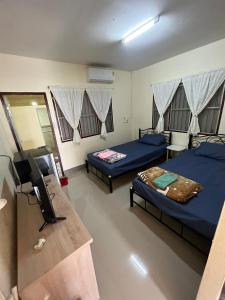 a room with two beds and a television in it at ทองอุไรโฮมสเตย์ ณ แม่สาย in Mae Sai
