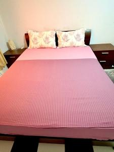 a pink bed with pink sheets and pillows at Studio in City Center Living at Heart of It All in Er Rachidia
