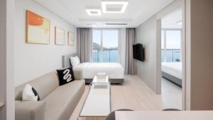 a living room with a couch and a bed at Elmomento Songdo in Busan