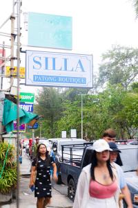 a group of people walking down a sidewalk under a sign at Silla Patong Boutique in Patong Beach