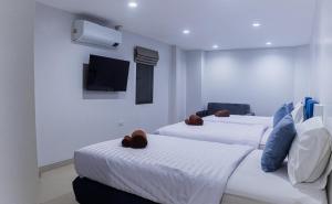 two beds in a room with a tv on the wall at Silla Patong Boutique in Patong Beach