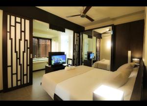 Domaine Des Alizees Residence في غراند بايَ: غرفة نوم بها سرير أبيض كبير وتلفزيون