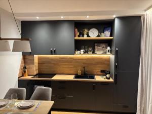 a kitchen with black cabinets and a sink and a table at Ski-in Flat Next to Ski Road at Mountain View in Bansko
