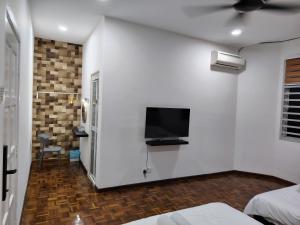 关丹YNY Guest House的一间白色墙壁上配有电视的卧室