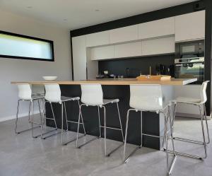 een keuken met witte barkrukken en een aanrecht bij Villa Ty Billou in Santec