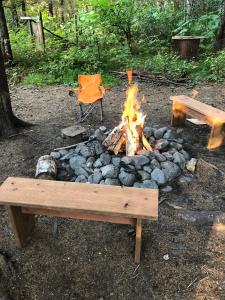 a fire pit with a bench and a picnic table at Nauti Otter Inn and Yurt Village in Bear Creek