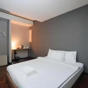 Cette petite chambre comprend un grand lit blanc. dans l'établissement XX GO INN SSilom - BTS Surasak, à Yan Nawa