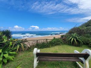 a bench sitting on the grass near a beach at The Beaches in Umtentweni