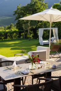 uma mesa com um guarda-chuva num pátio em Ansitz Battisti Suites em Caldaro
