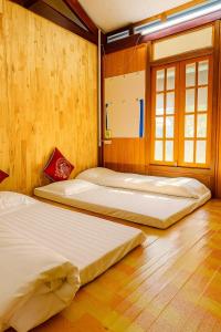 two beds in a room with wooden walls at Cầu Treo Homestay in Cham Ta Lao
