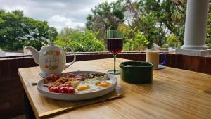 Een bord met ontbijt en een glas wijn op tafel. bij Jacaranda Escape in Pretoria