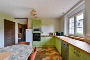 a kitchen with green cabinets and a table and a table and a dining room at La Maison Vert-Émeraude - Proche sentier randonnée in Arzal +4 photos