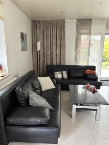 a living room with a black leather couch and a table at Ferienhaus 251 in Burhave in Burhave