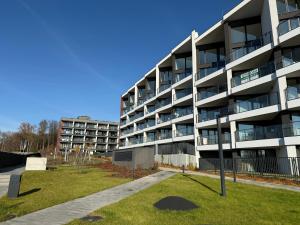 ein Mehrfamilienhaus mit einem grünen Rasen davor in der Unterkunft Apartament 13 Zegrze - Rezydencja Zegrze in Zegrze